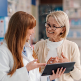 Ein Apotheker hat bei einem Kunden den Vitamin-D-Spiegel gemessen und bespricht mit ihm das Ergebnis.