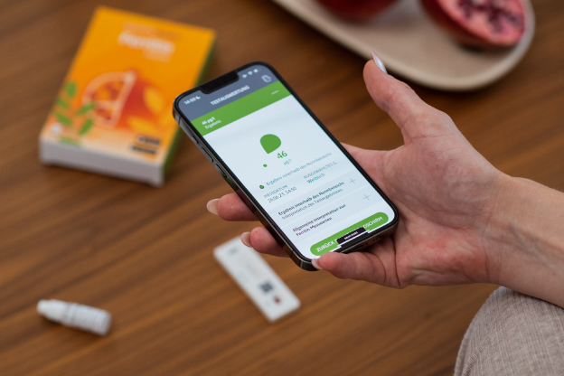 Person wertet einen Eisenmangel-Schnelltest mit einem iPhone und der SmarTest Ferritin-App aus, um ein Testergebnis zu erhalten.