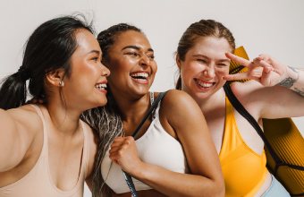 Froehliche Frauen in Sportbekleidung und mit Yogamatte.