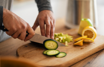 Nahaufnahme eines Holzbretts, auf dem Gurken und Zitronen fuer viele Naehrstoffe und Vitamine in der Ernaehrung geschnitten werden.
