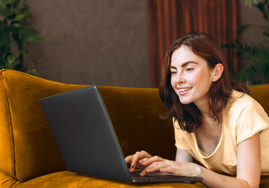 Person liegt auf einem Sofa und nutzt einen Laptop, um Schnelltest-Ergebnisse zu verwalten.