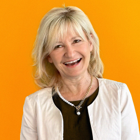 Portrait einer laechelnden Frau mit kurzen blonden Haaren auf orangenem Hintergrund.