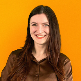 Portrait einer jungen laechelnden Frau mit langen dunklen Haaren auf orangenem Hintergrund.