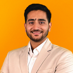 Portrait eines jungen laechelnden Mannes mit schwarzen Haaren und Anzug auf orangenem Hintergrund.
