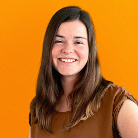 Portrait einer jungen laechelnden Frau mit langen braunen Haaren auf orangenem Hintergrund.