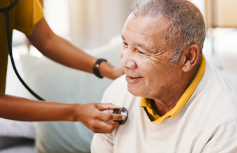 A doctor examining an older patient with a stethoscope for a heart condition.