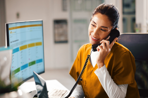Healthcare professional speaking on the phone at a workstation with the Preventis Portal displaying patient test results.